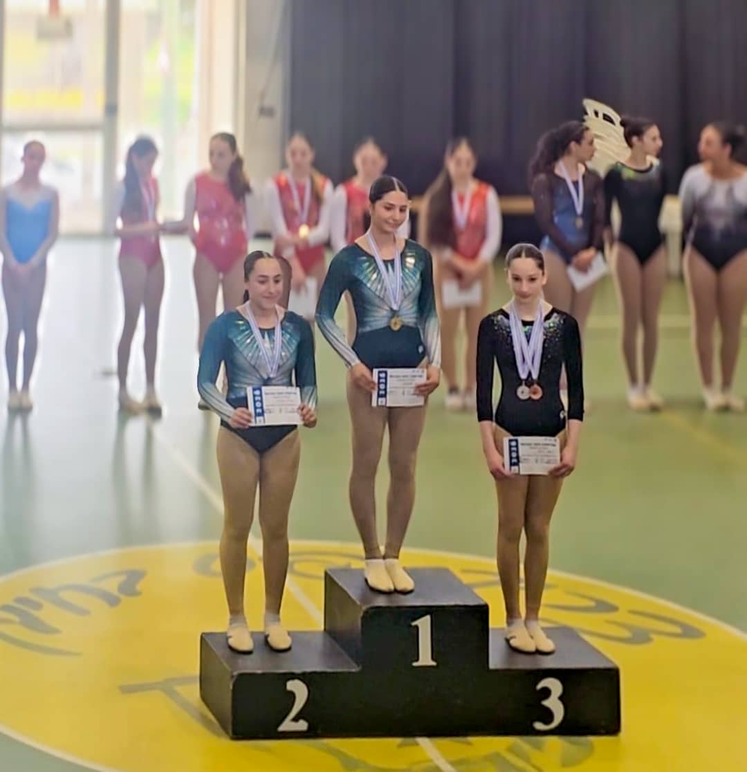 מתעמלות בתחרות התעמלות גלגלי ענק עומדות על הפודיום עם מדליה על צווארן