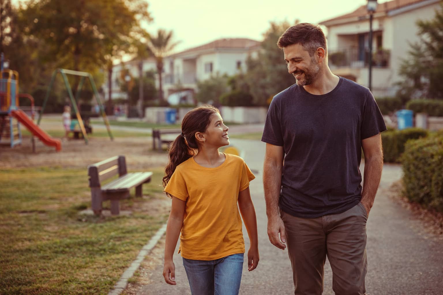 אבא ובת מטיילים בסביבת גן שעשועים
