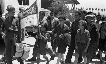 הילד ישראל אלו עם דגל תנועת "אגודתי", תנועת הנוער של בוכנוואלד (קרדיט: הארכיון הציוני המרכזי) הילד ישראל אלו עם דגל תנועת "אגודתי", תנועת הנוער של בוכנוואלד (קרדיט: הארכיון הציוני המרכזי)